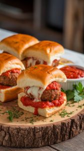 A serving dish of Meatball Marinara Sliders topped with chopped parsley, with gooey cheese and marinara sauce visible