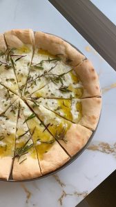 soft cottage cheese flatbread brushed with olive oil, sliced into pieces, with fresh herbs sprinkled on top