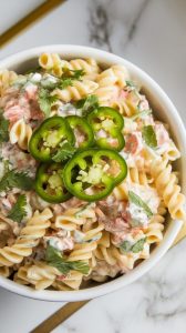 finished jalapeño pasta salad in a white serving bowl, topped with fresh chopped cilantro and a few extra jalapeño slices