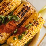 grilled corn with a final sprinkle of chili powder and chopped cilantro on top, glistening with butter.