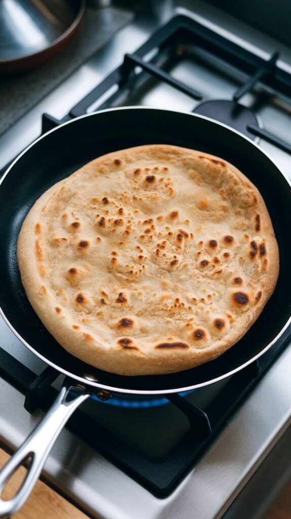 flatbreads grilling on a pan, with bubbles forming and light golden brown spots on the surface.