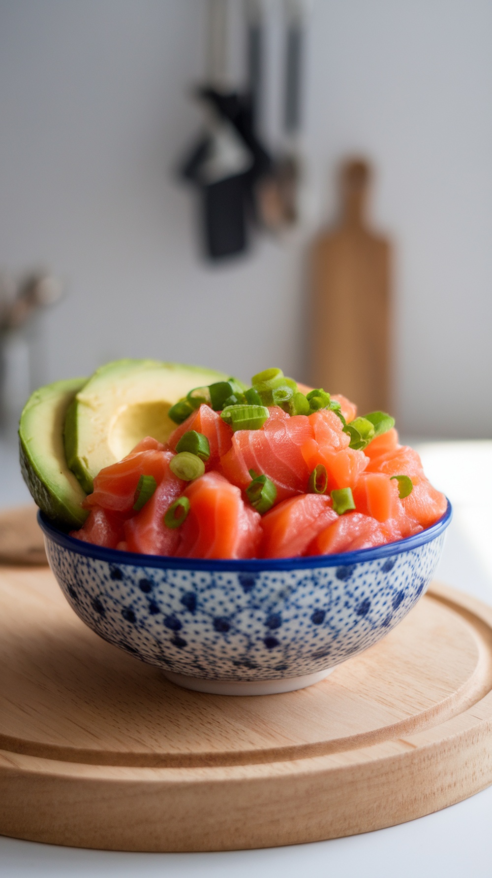 A bowl with salmon pieces and avocado slices on a wooden surface.