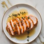 sliced chicken breast drizzled with apple cider glaze, garnished with fresh thyme.