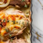 inished chicken bake garnished with fresh thyme, melted cheese slightly golden, onions glistening on top of juicy chicken.