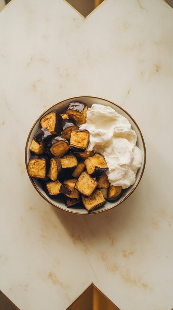 roasted golden eggplant cubes added beside cottage cheese in a bowl, textures and contrast popping.