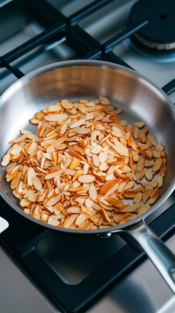 slivered almonds toasting in a dry skillet, golden brown edges starting to show.