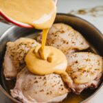 smooth, creamy honey mustard marinade being whisked in a bowl with visible garlic specks.