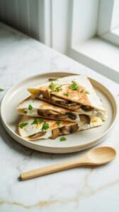 he finished quesadilla sliced into triangles on a ceramic plate, filled with creamy cottage cheese and mushrooms.