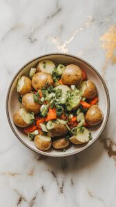 finished harissa potato salad with roasted carrots in a shallow serving bowl, topped with chopped scallions and herbs