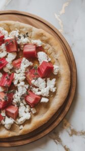 finished flatbread being sliced with fresh thyme sprinkled on top and honey glistening over the goat cheese. White