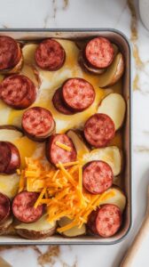 baking dish filled with roasted potato halves and browned kielbasa slices, topped with poured egg mixture and a layer of shredded cheddar cheese