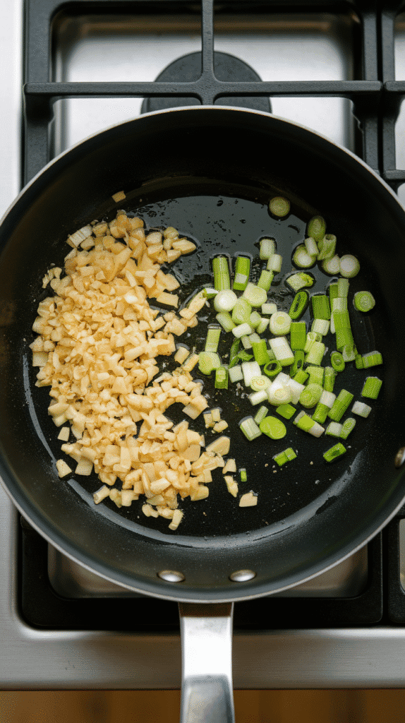 minced garlic and chopped scallion whites sizzling gently in oil, edges golden and fragrant.