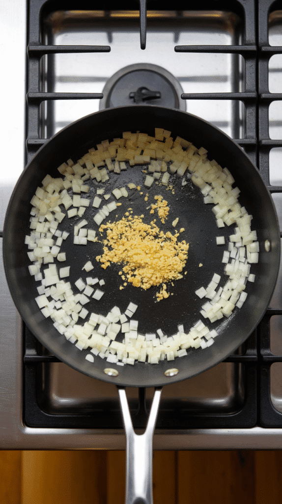 diced onions sautéing in melted butter, with minced garlic just added to the pan, everything starting to soften and become fragrant.