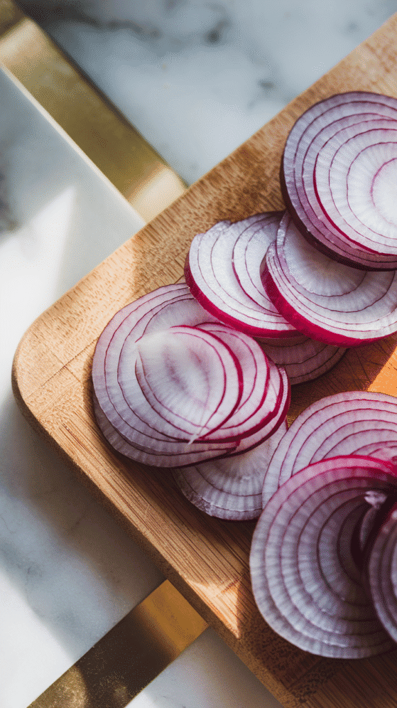 raw shallots sliced into thin rings on a wooden cutting board, delicate and translucent.