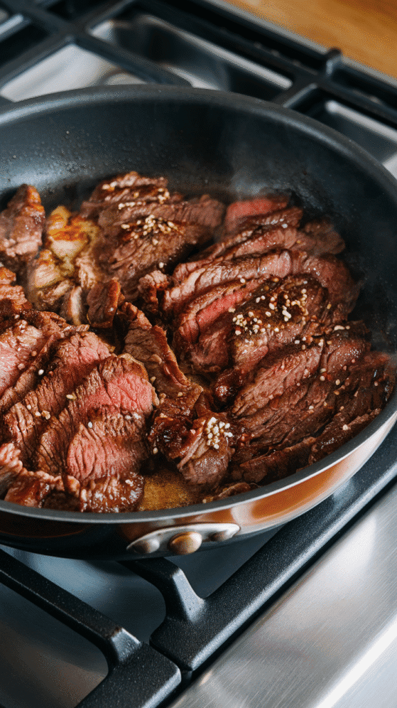 bulgogi beef slices sizzling in a hot pan, caramelizing around the edges, sauce thickening and clinging to the meat.