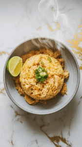 lemongrass chicken fried rice served in a gray ceramic bowl with a lime wedge on the side, green onion garnish on top,